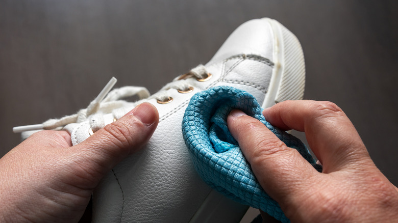person wiping cloth on sneakers