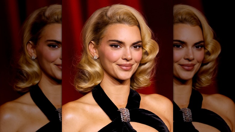 Kendall Jenner smiling with a blonde hair styled in classic curls