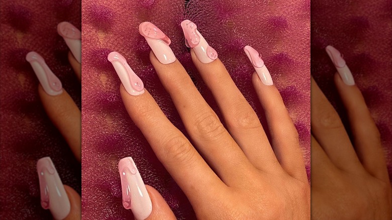 A resting hand showing pink nails with a 3D drip design