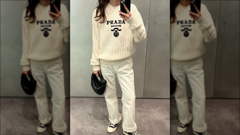 Person in Prada sweater with white jeans