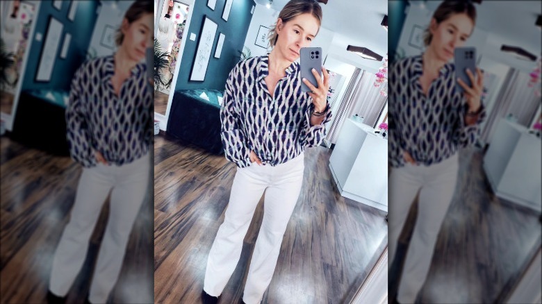 Woman in white jeans and button-up top taking selfie