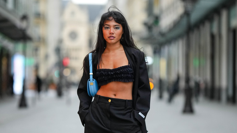 A young woman wears a black bra as a top 