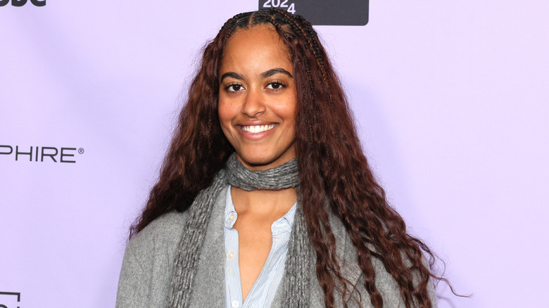 Malia Obama smiling against a purple backdrop at Sundance Film Festival