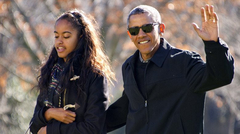 Malia Obama walking next to her father Barack Obama as he waves to the camera