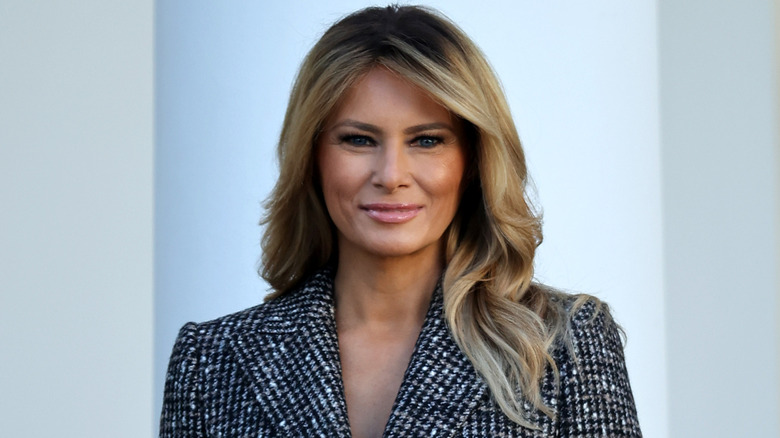 Melania Trump with long blond hair in a black and white coat at an event