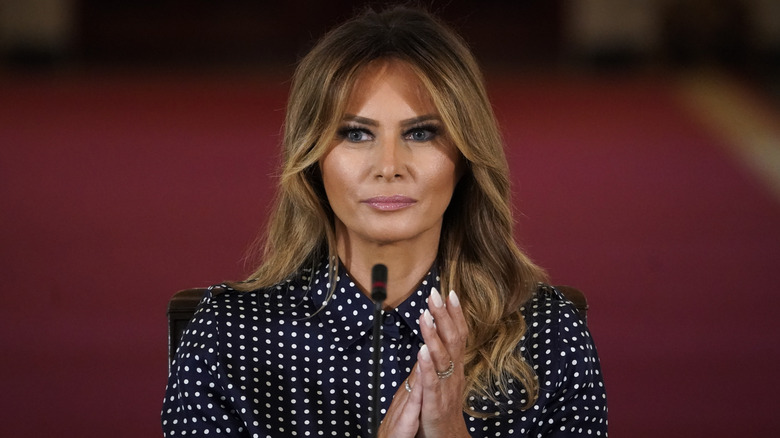 Melania Trump in a polkadot shirt in front of a microphone