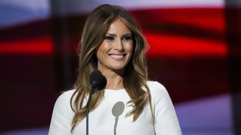 Melania Trump in a white dress speaking to an audience