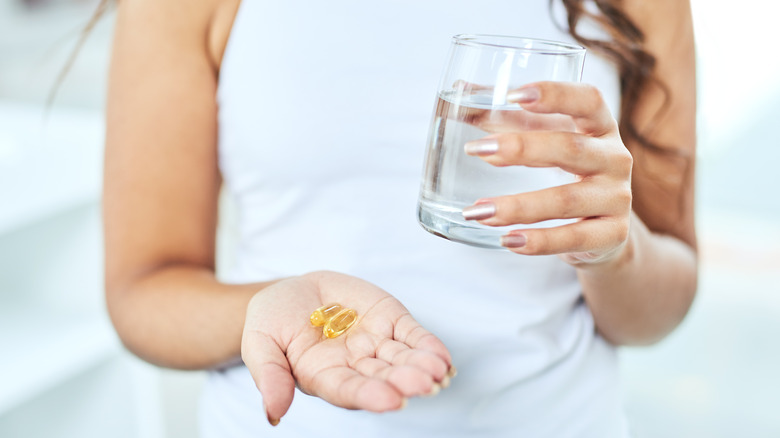 Woman holding vitamins and water