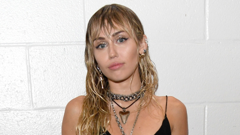 Miley Cyrus backstage with wet curls and a black, sleeveless dress