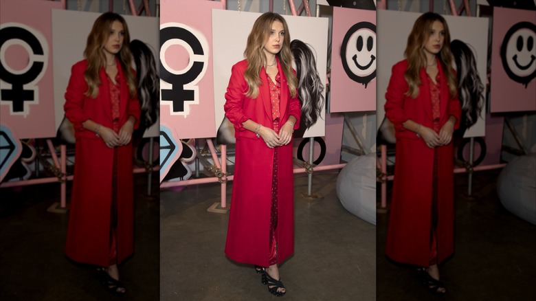 Millie Bobby Brown looking off-camera while wearing a bold red ensemble