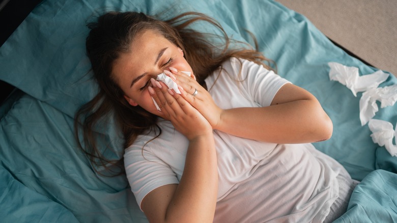 person blowing nose in bed