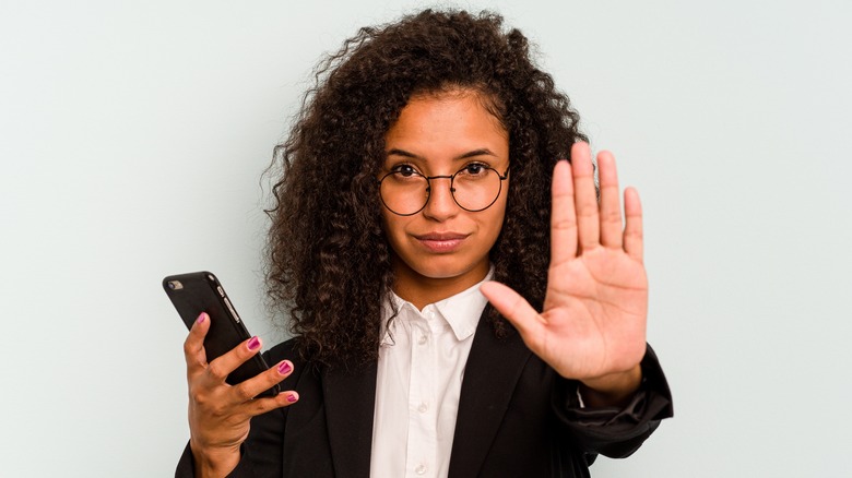 A woman holding a phone with her hand up