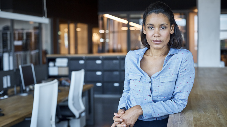 Woman of color looks at viewer while standing in workplace