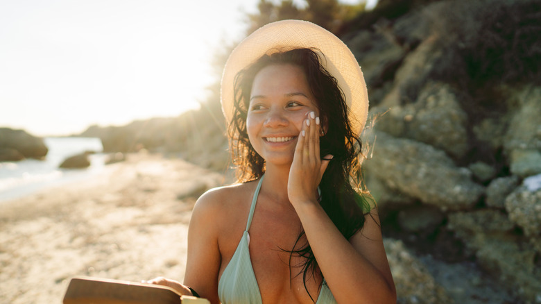 A woman looking at her face in a small mirror and touching her cheeks