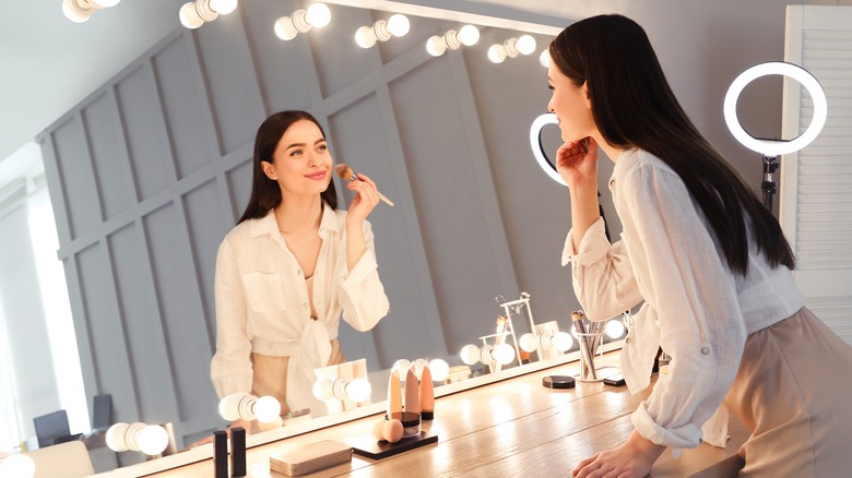 Woman applying makeup in mirror