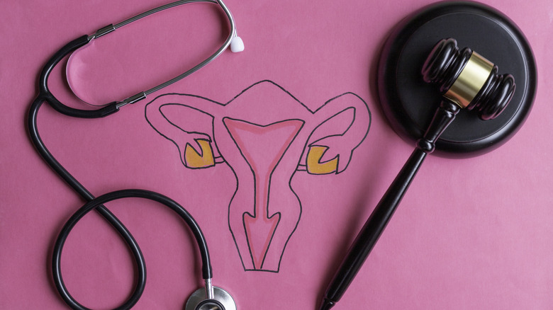 Stethoscope, uterus, and gavel on pink background