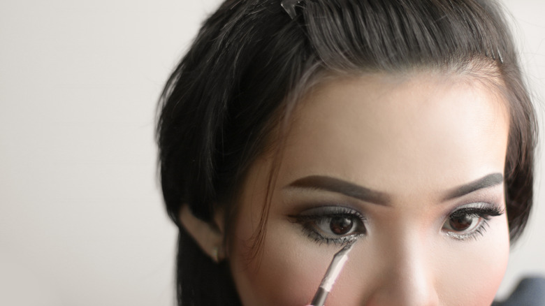 Woman applying eyeshadow to waterline
