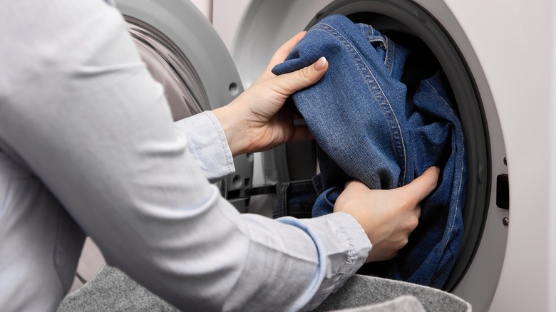 Person putting jeans into a washing machine