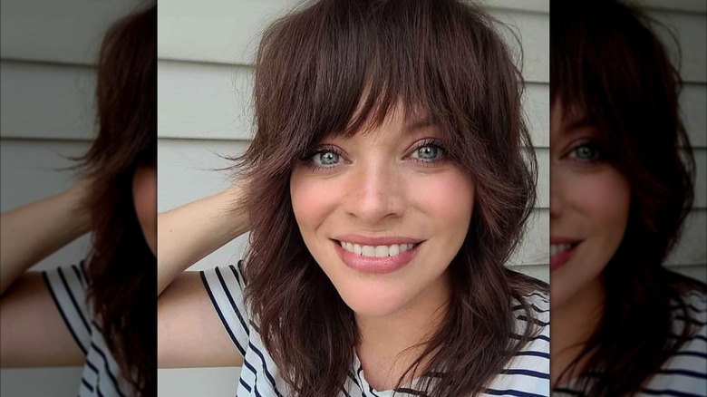 Smiling woman with brunette hair and a wolf cut