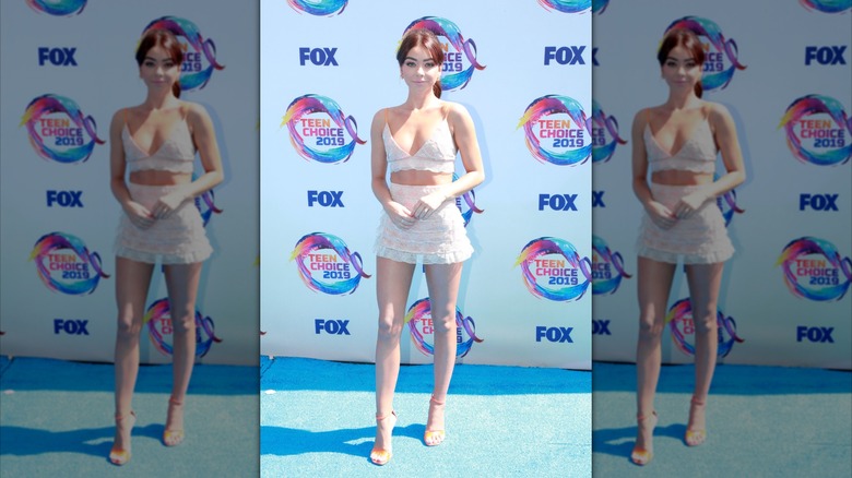 Sarah Hyland wears a lace set in front of a step and repeat