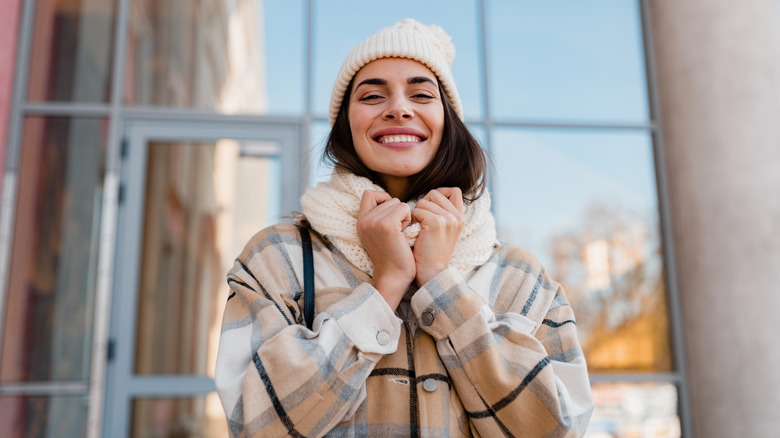 A woman in a plaid coat and a knitted scarf and beanie