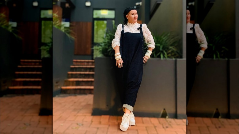 Person in denim overalls with bracelets