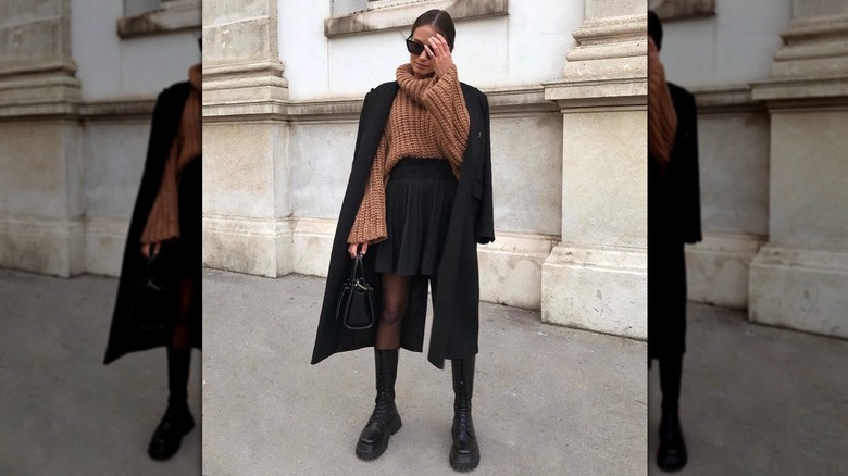 Woman in a brown chunky sweater and black skirt