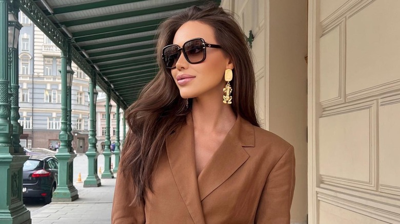 A woman in a Mocha Mousse jacket and gold earrings