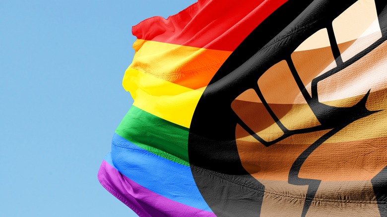 An arm holds a rainbow striped flag with a black fist in the center