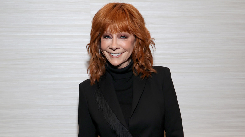 Reba McEntire smiling into the camera at the 2024 Super Bowl pre-game event