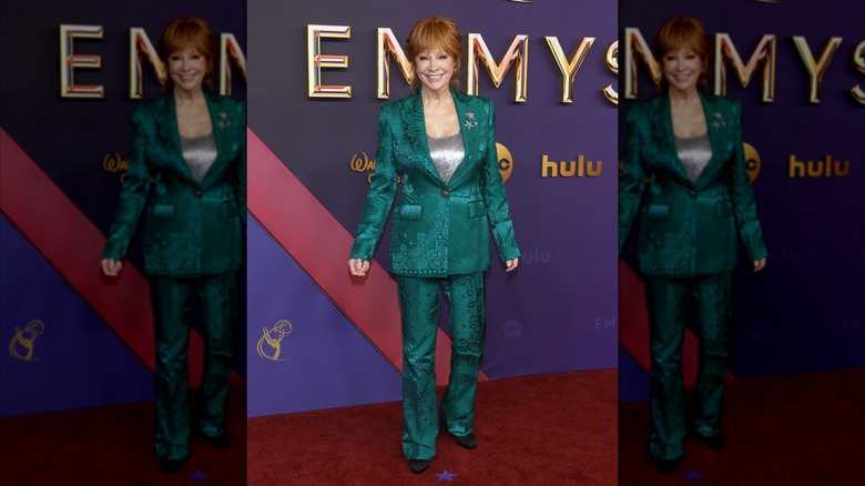 Reba McEntire smiling while wearing a pattern green suit and silver top