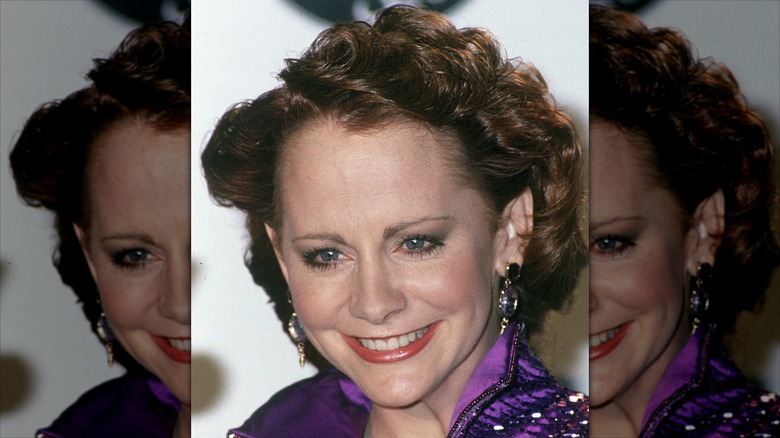 Reba McEntire smiling on the red carpet with thin eyebrows