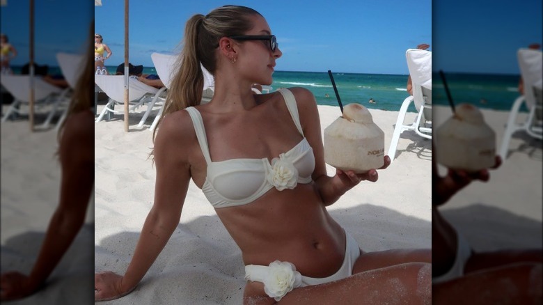 Eirunn sips coconut water in a bikini on  the beach