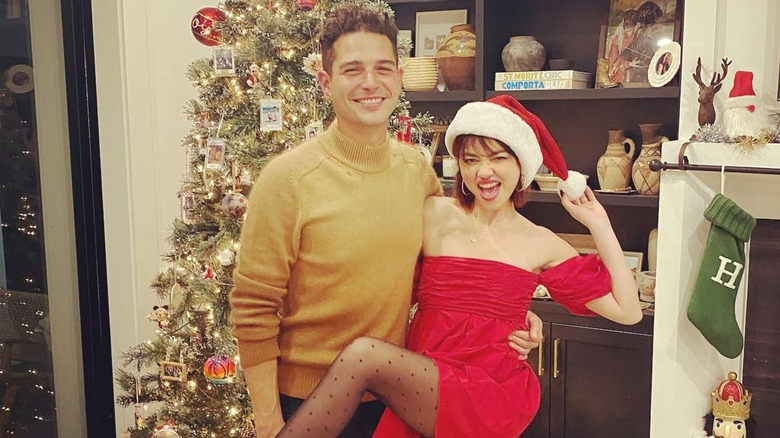 Wells Adams and Sarah Hyland posing next to a Christmas tree