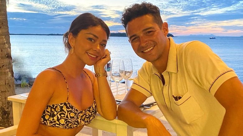 Sarah Hyland sitting with Wells Adams on a beach