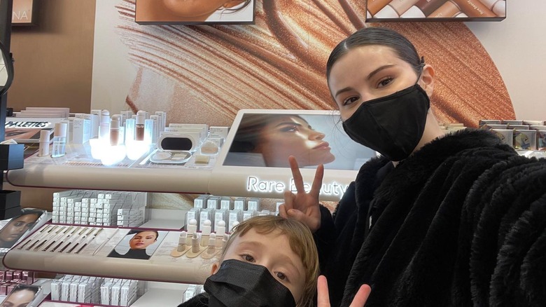 Selena Gomez posing with her sister next to Rare Beauty products