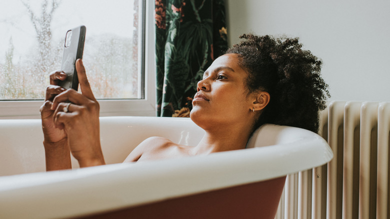 Woman looking at her phone in the bath