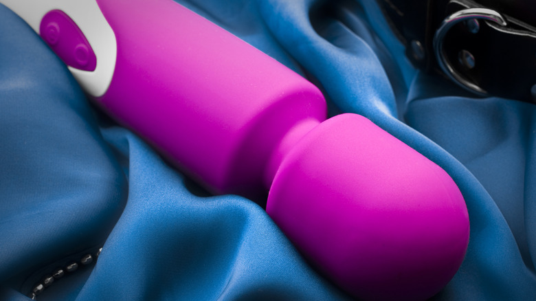 Pink wand massager vibrator on blue silk sheets