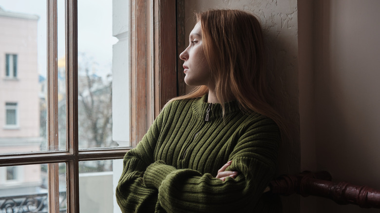 A woman in a green sweater looking out the window