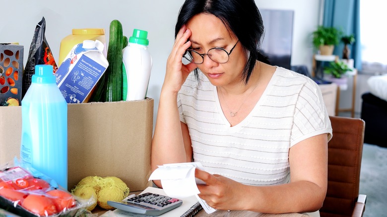 woman with groceries frustrated about expenses