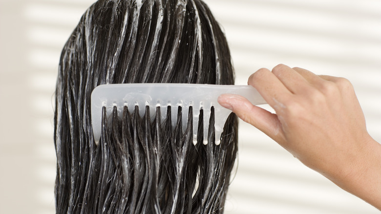person combing conditioner through hair