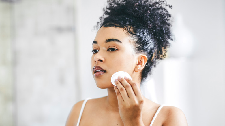 Woman putting on skincare with cotton pad