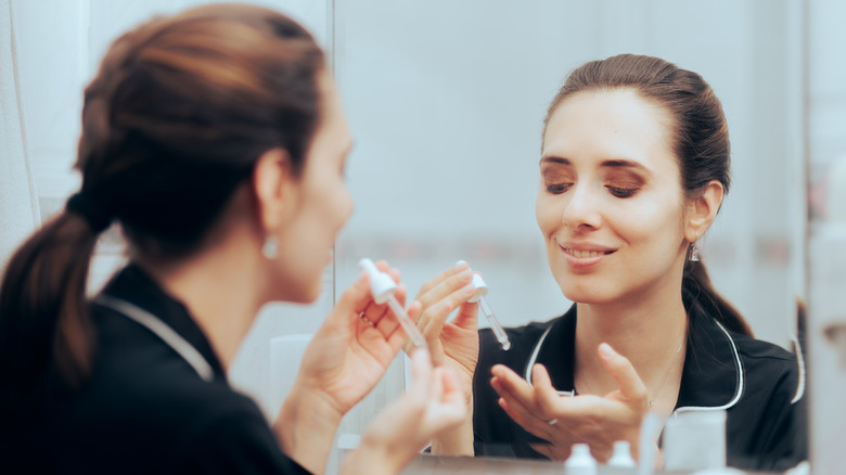 Woman applying skincare with eyedropper