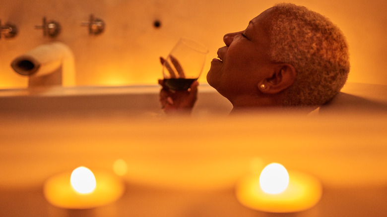 Woman relaxing in bath with wine in hand