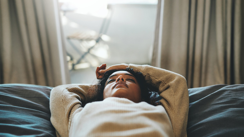 Woman laying down on bed with eyes closed