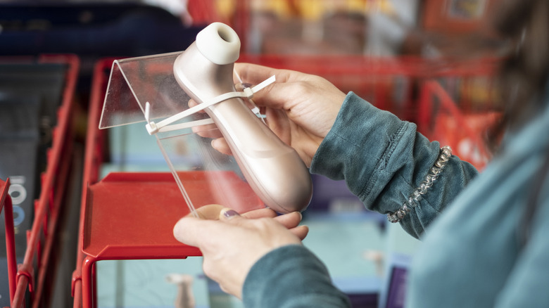 Person looking at a Satisfyer clitoral stimulator at a store