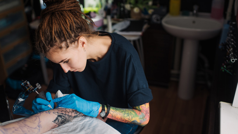 Tattoo artist creating an arm tattoo