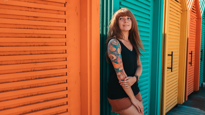 Person with tattoo sleeve posing by colorful doors