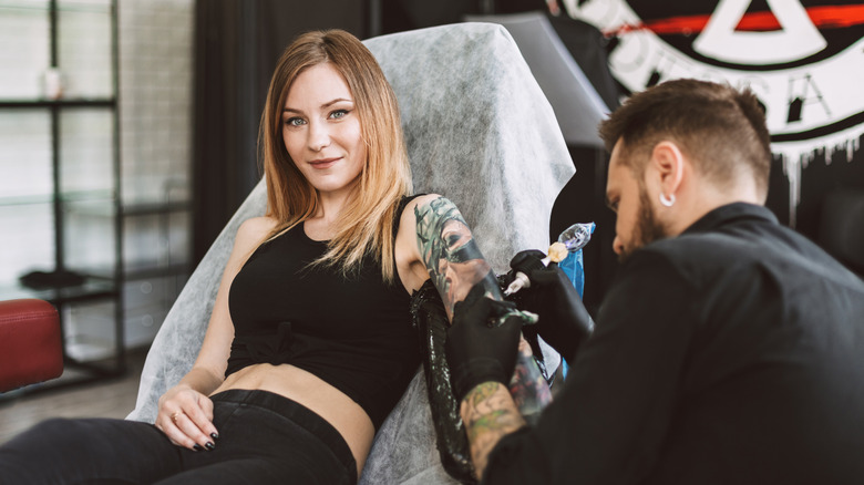 woman smiling while getting tattoo sleeve