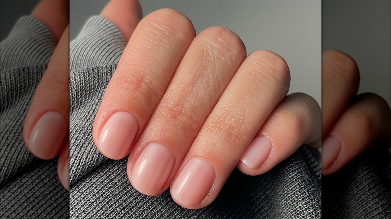 Close-up of finger closed over a sleeve with sheer, nide-colored nails